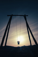 Silhouette of adult woman enjoying on a giant swing