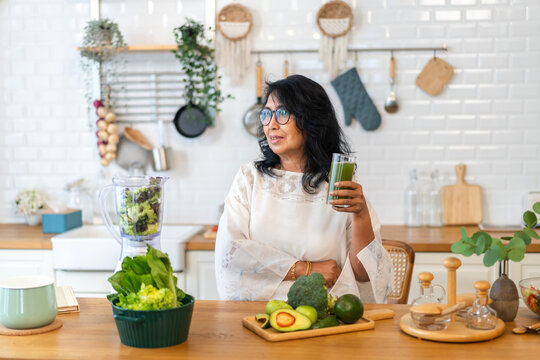 Portrait Senior Healthy Asian Woman Making Green Vegetables Detox Cleanse And Green Fruit Smoothie With Blender.elderly Woman Drinking Glass Of Green Fruit Smoothie In Kitchen.healthcare, Insurance.