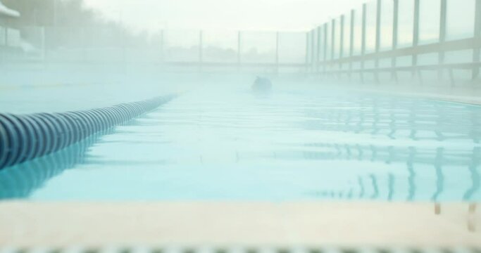 fit sporty girl in bathing cap and goggles training in thermal swimming pool, blurred background Slow motion. woman swimming in hot spring thermal pools bath at luxury health center