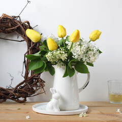 easter composition. a spring bouquet, yellow tulips and white lilac in a jug. easter bunny...