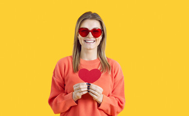 Pretty girl wishes you happy Valentine's Day. Beautiful young lady in heart shaped sunglasses...