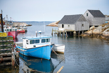Fototapeta na wymiar Fishing boats at iconic Peggy's Cove Lighthouse of Nova Scotia
