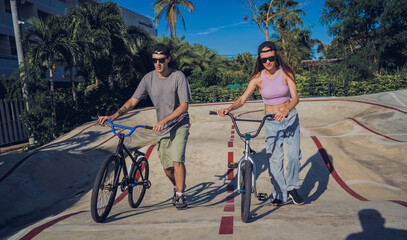 Young happy couple enjoy BMX riding at the skatepark