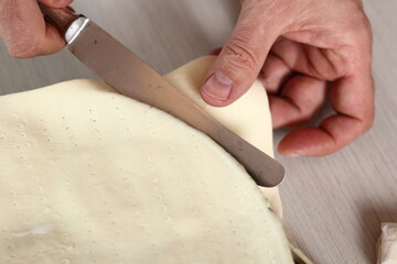 Trim off excess of puff pastry with knife. Making Pear Tarte Tatin with Cardamom series.