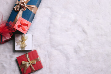 Various presents gift boxes with ribbon on fur rug with space for text. Boxing day sale seasonal promotion background. 