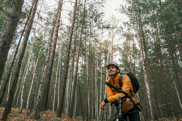 Fototapeta premium active lifestyle.A cyclist in equipment with a backpack stopped in the autumn forest and leaned on the bike to rest.Mountain Bike