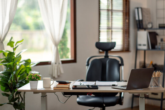 Laptop Computer, notebook, and eyeglasses sitting on a desk in a large open plan office space after working hours	