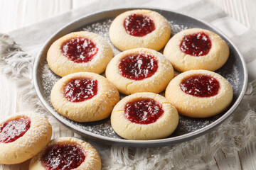Hallongrottor Swedish Thumbprint Cookies closeup on the plate on the white wooden table. Horizontal