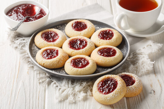 Thumbprint or Hallongrottor Swedish Raspberry Jam Cookies closeup on the plate on the white wooden table. Horizontal