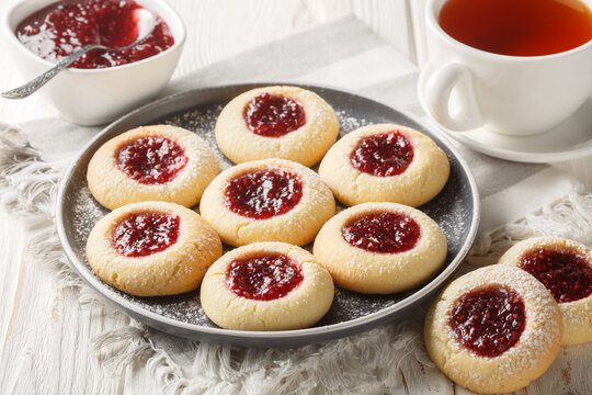 Hallongrottor or Swedish rapsberry caves jam cookies closeup on the plate on the white wooden table. Horizontal