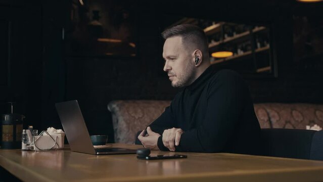 Portrait of an elegant man in a cafe with a laptop. A manager holds a video conference with colleagues or friends. Communication via video call.