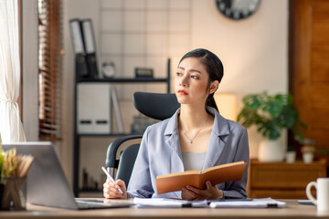 Sad Young woman employee having problems about her debts and financials. Frustrated Asian Beautiful businesswoman feeling depression, exhausted, tired, lazy during working at the office.
