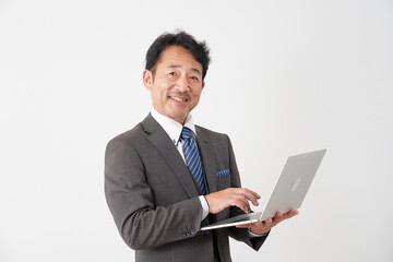 ノートパソコンを使う中年のビジネスマン　白背景　カメラ目線