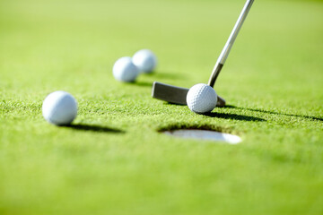 Closeup, golf and ball with club for shot in hole for practice, exercise or wellness to relax on grass. Sports, course or target for challenge on field in summer for competition, recreation or hobby