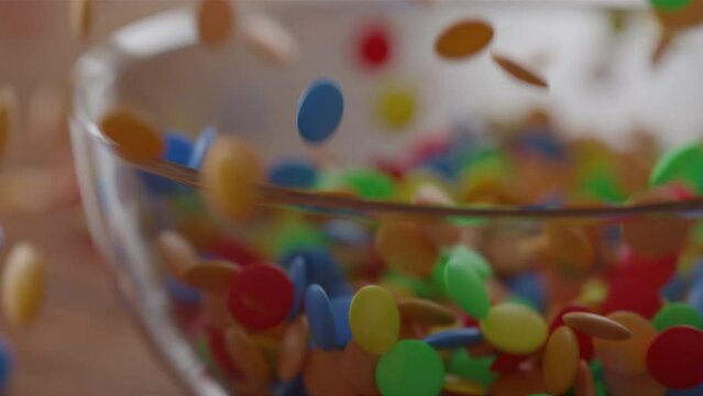 Many Chocolate Lentils Falling into a glass Bowl in slow motion