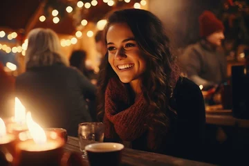 Poster Portrait of a young woman sitting at the table at the Christmas market and happily talking to someone. © Irina