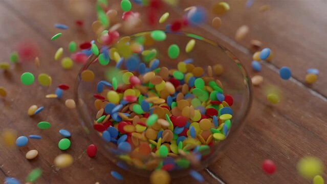Chocolate Lentils Falling into a glass Bowl on a wooden table