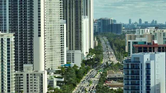 View from above of luxurious high-rise hotels and condos on Atlantic ocean shore in Sunny Isles Beach city. Urban street with busy traffic. American tourism infrastructure in southern Florida