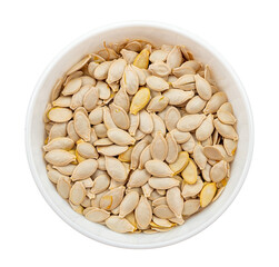 Pumpkin seeds in husks on a plate on a white background. View from above. Unshelled pumpkin seeds isolate
