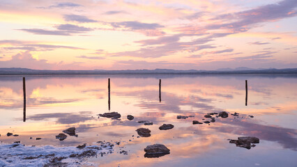 Sunset on the salt lagoon with reflections of clouds and silhouettes of reflections