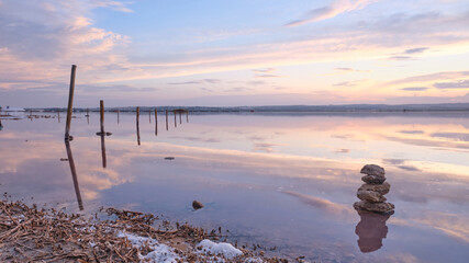 Sunset on the salt lagoon with reflections of clouds and silhouettes of reflections