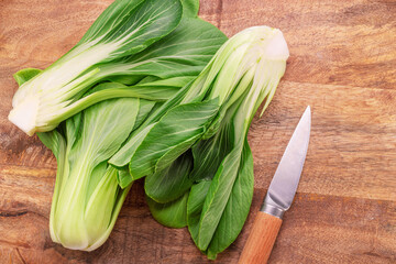 Bok choy or chinese cabbage on wooden background. View above. - obrazy, fototapety, plakaty
