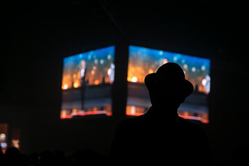 silueta de hombre con sombrero, en una convención - obrazy, fototapety, plakaty