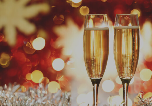 Glasses with champagne on the background of christmas decorations. Glasses of sparkling champagne on blurred holiday background. New year mood and celebration. Christmas night.