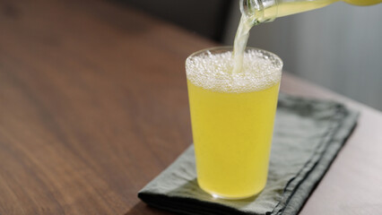 pour lemonade in tumbler glass on wood table