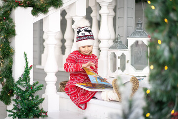 A little beautiful child reads a fairy tale in a book. Concept New Year, Merry Christmas, holiday,...