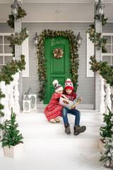 Children reading an interest book sitting on the bed against the decorated Christmas tree