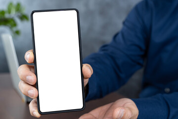 Hand holding smartphone with blank screen. Businessman touching screen of smart phone at office, using smartphone blank screen frameless modern design.