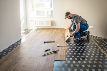 Professional worker joining vinyl floor covering at home renovation - obrazy, fototapety, plakaty