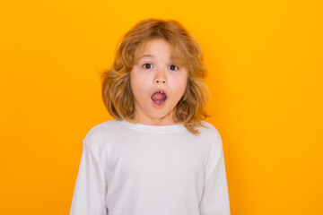 Excited child boy on yellow studio isolated background. Surprised face, amazed emotions of child.