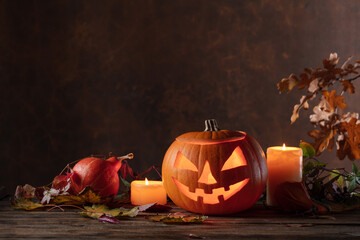 Halloween pumpkin head jack lantern with dried-up leaves.
