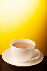 Cup of milk tea on yellow background