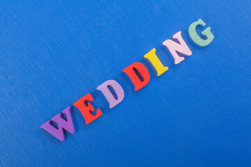 WEDDING word on blue background composed from colorful abc alphabet block wooden letters, copy space for ad text. Learning english concept.