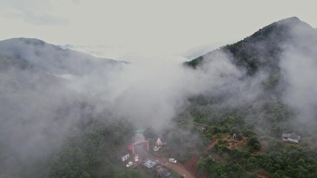 An aerial view of a misty atmosphere atop mountains, a road, and a doorway