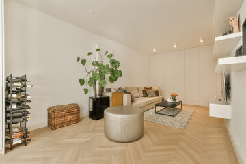 a living room with white walls and wood flooring, there is a large plant in the center of the room