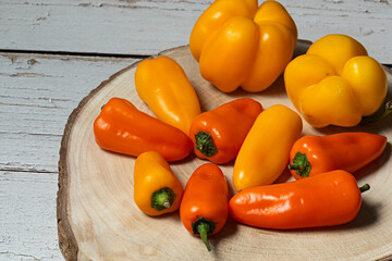 Pimientos naranjas y amarillos sobre tabla de madera.