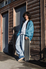 teenager with skateboard on street wall