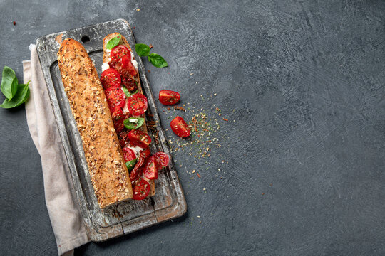 Fresh baguette with Caprese. Delicious sandwich with with tomatoes and mozzarella cheese with fresh basil leaves. Italian food conception.