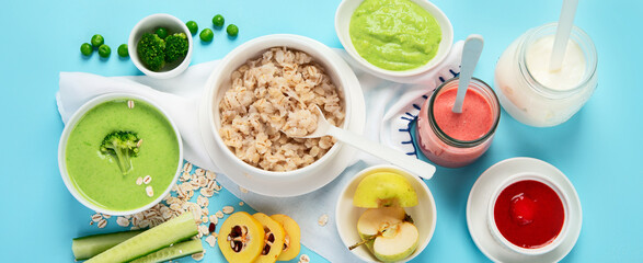 Bowls with healthy baby food on blue background.