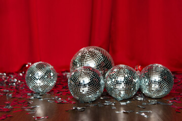 Five big mirror disco balls close up on the floor against the background of red curtains. disco party ball. Silver metophane.