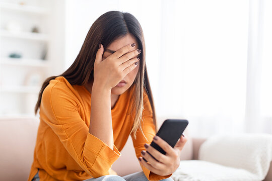Upset Confused Woman Holding Smartphone At Home