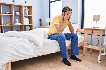 Young man stressed sitting on bed at bedroom