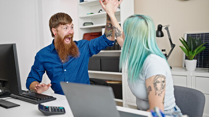 Obraz premium Man and woman business workers using laptop and computer high five for achievement at office