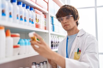 Young blond man pharmacist holding pills bottle at pharmacy