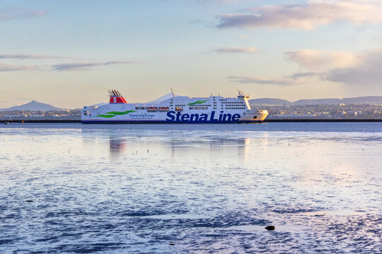 "Stena Line" ferry boat "Stena Adventurer" sails into Dublin Port on calm day with blue reflections in low tide water pools. Ireland