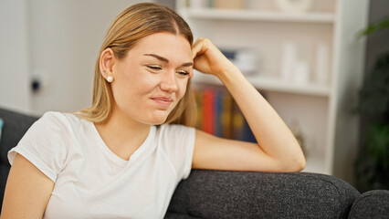 Fototapeta premium Young blonde woman smiling confident sitting on sofa at home